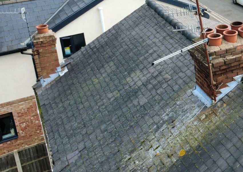 Aerial drone view of a slate roof, chimney stack and surrounding rooflines