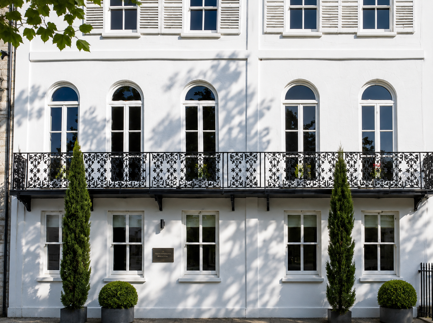 White painted Georgian townhouse facade with arched windows and ornate cast iron balcony railings